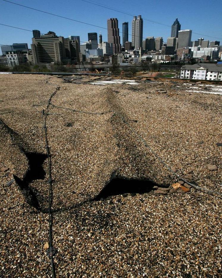 A roof torn open by a tornado, with the Atlanta skyline beyond