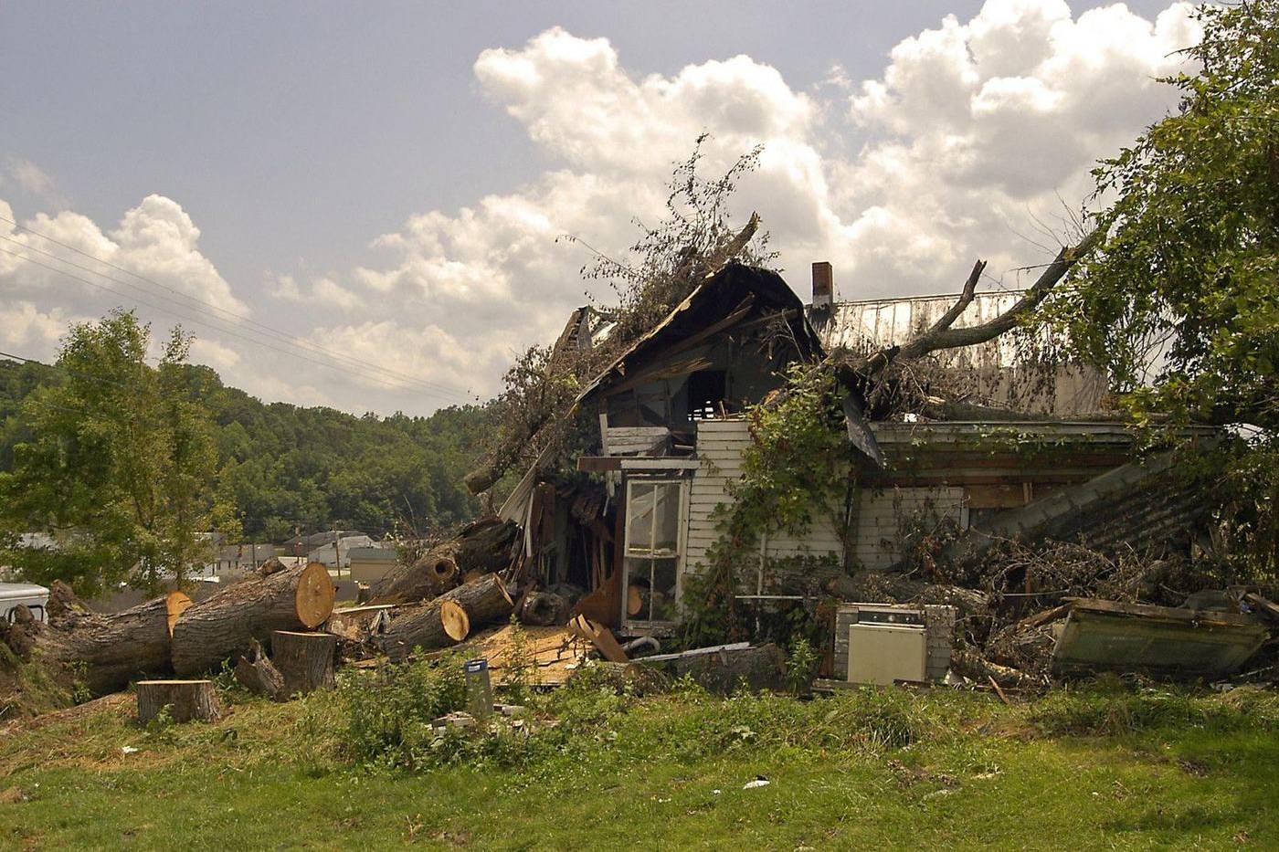 A house buried under fallen trees after a tornado